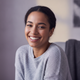Close-up portrait of a smiling young woman with warm skin tones, conveying happiness and trust.